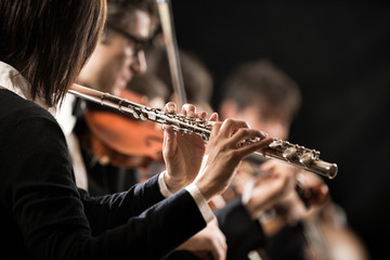 Female flutist with orchestra on stage © stokkete