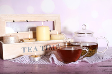 Composition with tea in cup and teapot and candles