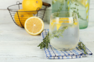 Tasty cool beverage with lemon and thyme, on wooden background