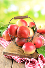 Naklejka na ściany i meble Sweet apples in wicker basket on table on bright background