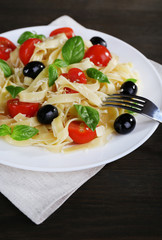 Spaghetti with tomatoes, olives and basil leaves