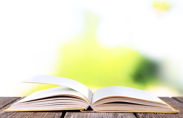 Open book on wooden table on natural background
