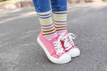 Fototapeta na wymiar Female legs in colorful socks and sneakers outdoors