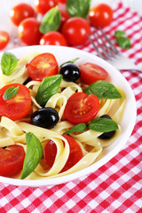 Spaghetti with tomatoes, olives and basil leaves