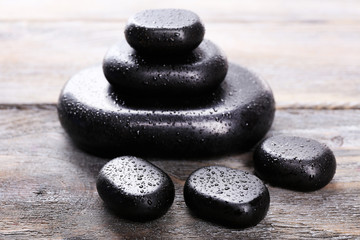 Spa stones with drops on wooden background