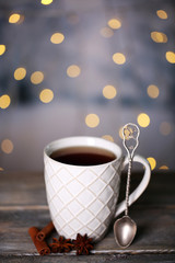 Cup of tasty hot tea, on wooden table, on shiny background