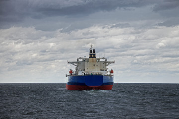 A large cargo ship at sea on a cloudy day.