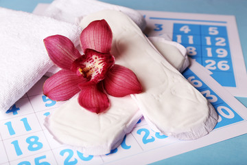 Obraz na płótnie Canvas Sanitary pads and lilac orchid on blue calendar background