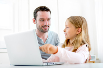 Father and his blond daughter using laptop