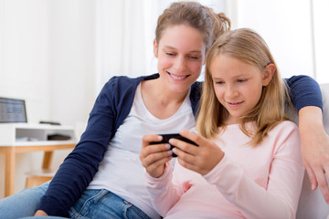 Attractive woman and little sister using mobile