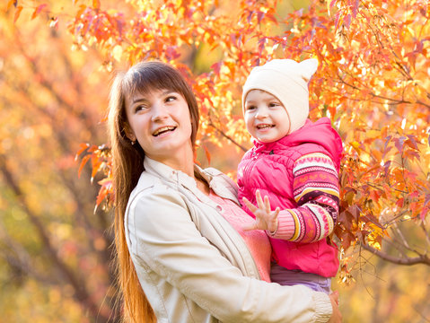 beautiful mother with kid girl outdoors in autumnal park