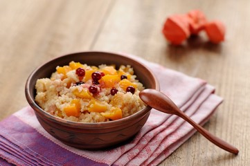 Millet porrige with pumpkin in clay bowl with wooden spoon