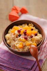 Millet porrige with pumpkin in clay bowl with wooden spoon
