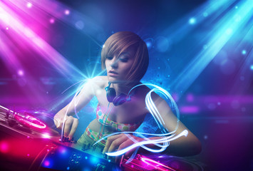 Fototapeta na wymiar Energetic Dj girl mixing music with powerful light effects