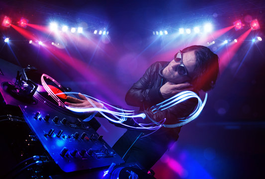 Disc jockey playing music with light beam effects on stage