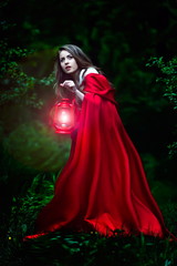 beautiful woman with red cloak and lantern in the woods