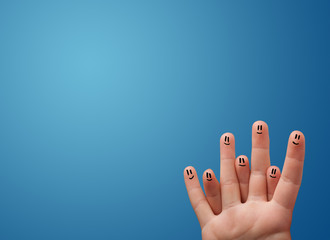 Happy smiley face fingers looking at empty blue background copy