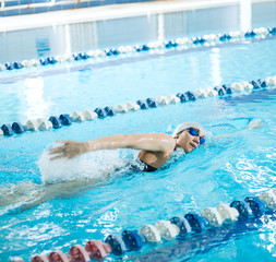 Young girl in goggles swimming front crawl stroke style