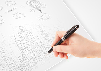 A person drawing sketch of a city with balloons and clouds on a