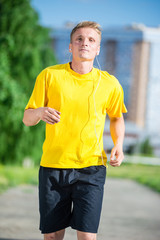 Sporty man jogging in city street park. Outdoor fitness.