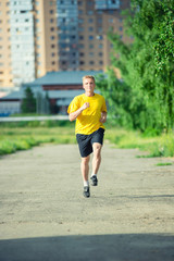 Fototapeta premium Sporty man jogging in city street park. Outdoor fitness.