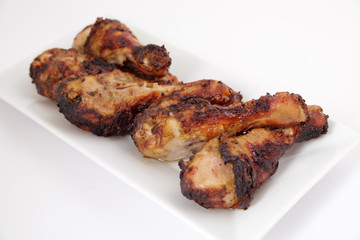 Grilled chicken legs (drumsticks) on white plate