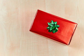 Red gift box with bow on wooden table and space for text