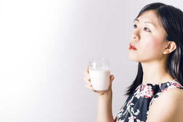 Thoughtful asian woman drinking milk