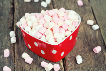 marshmallows in heart shape bowl on a wooden table