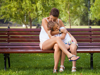 Mother and her little daughter sitting on the bench