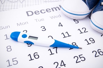 Electronic thermometer in fertility concept on calendar