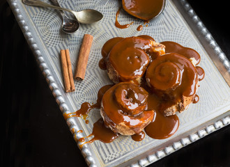 Cinnamon rolls with warm caramel topping and cinnamon sticks on