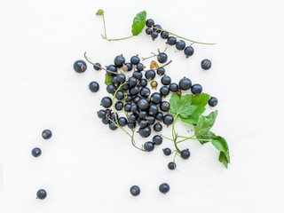 Black-currant berries and green leaves over a white wooden sufra