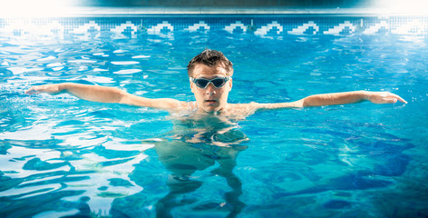 young male swimmer taking a breath and relaxing at pool