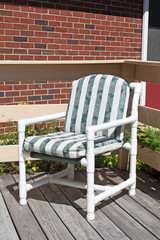 A generic PVC constructed lawn chair on a wood deck