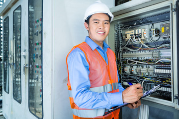 Asian Electrician at panel on construction site