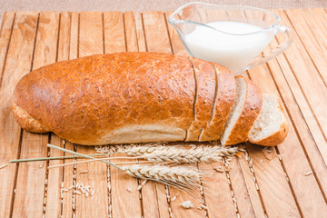 Fresh sliced loaf with bran and milk on a wooden  background