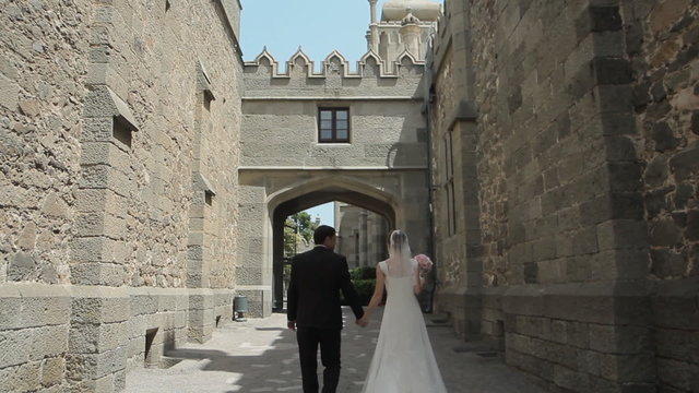 Young bride and groom go through the ancient streets of the