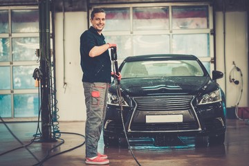 Man worker washing luxury car on a car wash