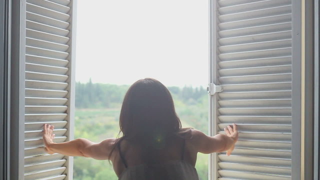 Girl opens the window in the morning, slow motion