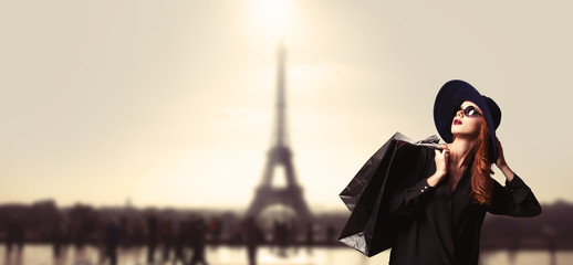 Redhead women with shopping bags on parisian background.