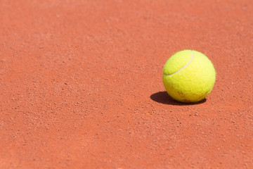 Tennis ball on a clay court.