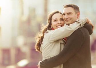 Fototapeta premium Young couple embracing in the sity street and looking happy.