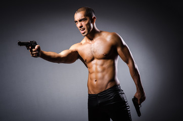 Fototapeta na wymiar Ripped man with gun against grey background