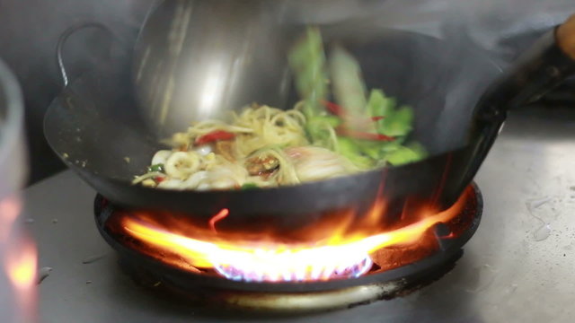chef cooking spicy seafood spaghetti in kitchen