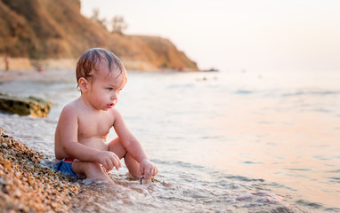 Fototapeta na wymiar Happy toddler boy playing on the sea
