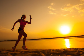 Woman running alone at beautiful sunset in the beach
