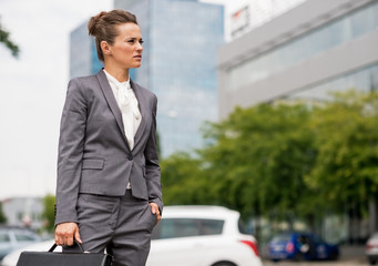 Business woman with briefcase standing in office district 