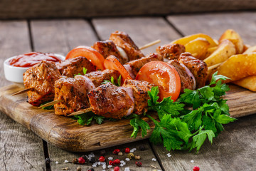 meat skewers with potatoes on the board