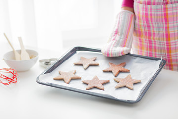close up of woman with cookies on oven tray
